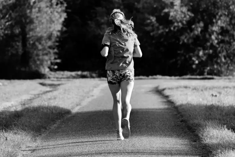 Mujer corriendo por un camino en la práctica de un hábito positivo.