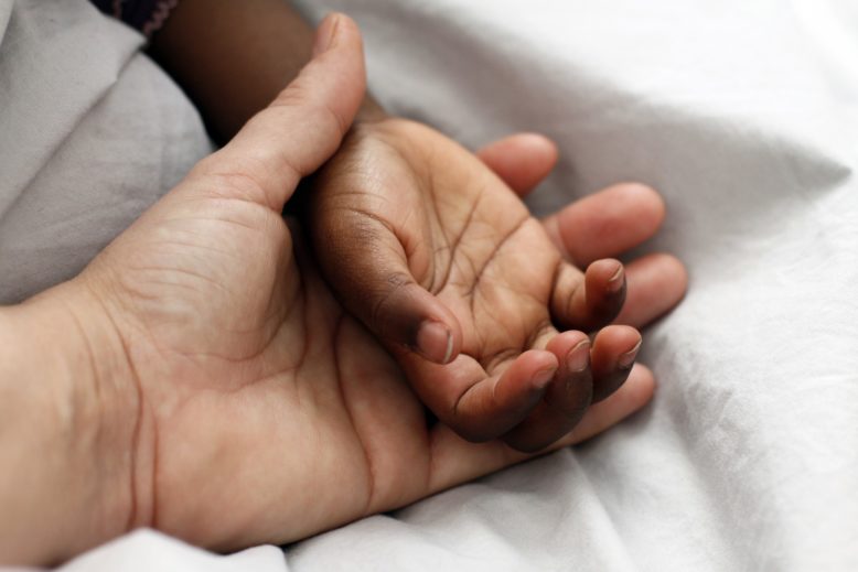 mano de adulto sostiene a mano de niño en adopción